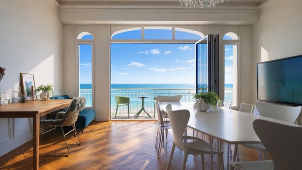 A spacious room with a wooden floor, a dining table, chairs, a TV, and a view of the ocean through large windows. - Magnificent sea view flat Les Sables - 7 pers (Les Sables-d´Olonne)