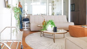 A modern living room with a beige sofa, a round coffee table with a plant, and a metal cart. - Magnificent sea view flat Les Sables - 7 pers (Les Sables-d´Olonne)