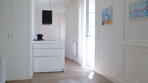 A hallway with a white cabinet, a black appliance, and a door leading to a bright room. - Flat fishing port Les Sables - 4 pers (Les Sables-d´Olonne)