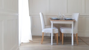 A dining table with white chairs, a white tablecloth, and a set of glasses and plates. - Flat fishing port Les Sables - 4 pers (Les Sables-d´Olonne)