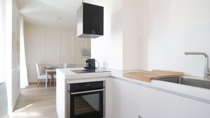 A modern kitchen with white cabinetry, a built-in oven, a coffee machine, and a wooden countertop. - Flat fishing port Les Sables - 4 pers (Les Sables-d´Olonne)