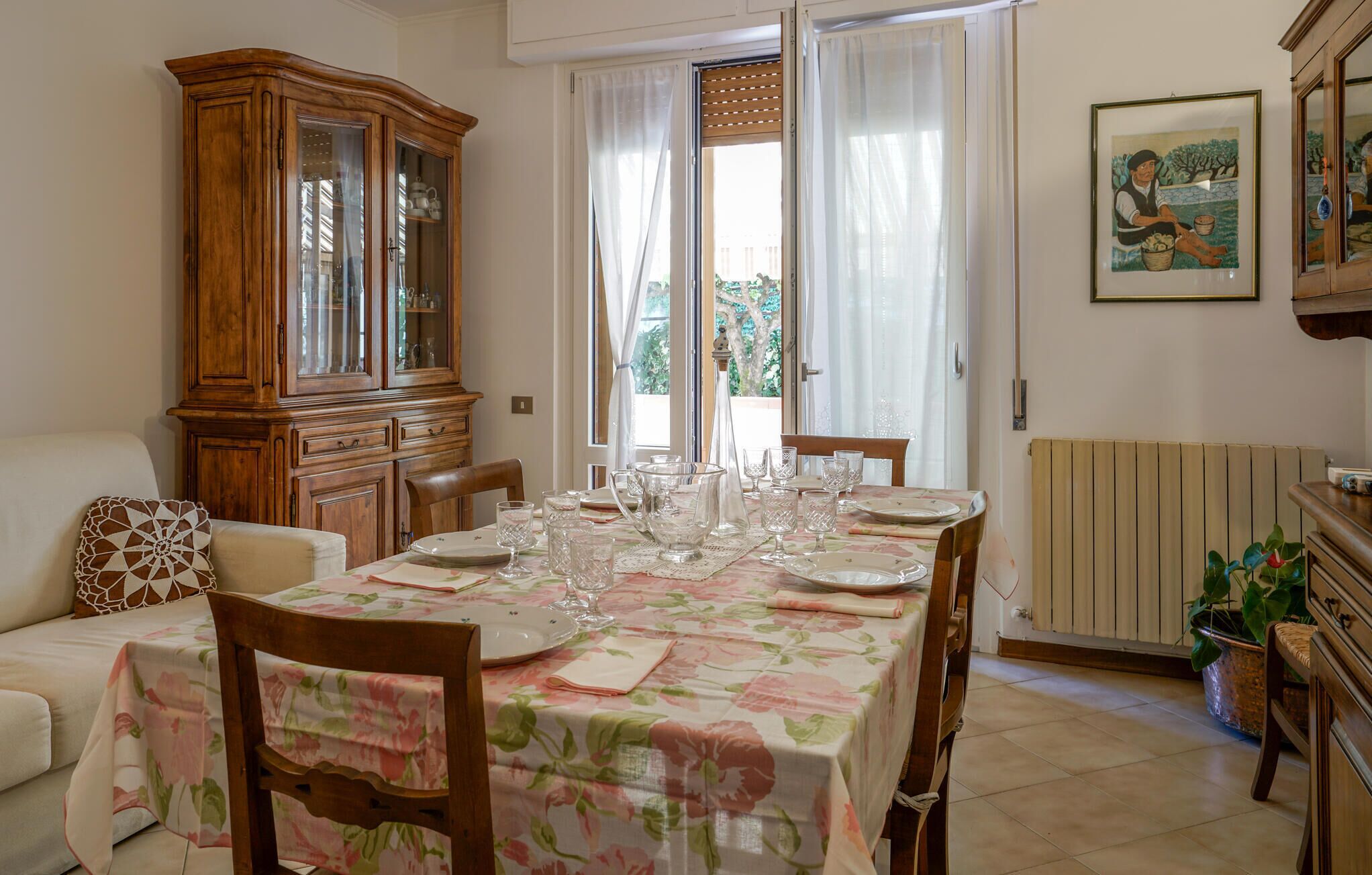 Un comedor con una mesa preparada para cuatro personas, un armario de madera y un radiador.