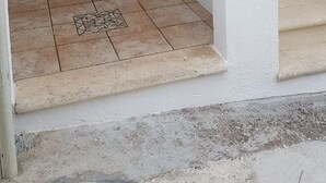 Eine Treppe führt zu einem Raum mit einer Holztür und einem kleinen, runden Gegenstand an der Wand.