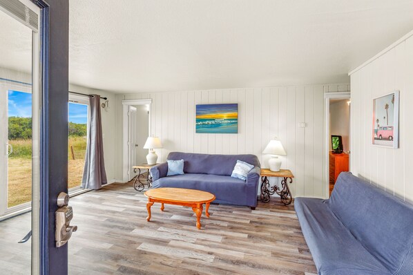 Relax in a spacious living area with a comfortable sofa, wooden coffee table, and large window offering scenic views.