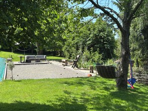 Un espace patio aménagé avec du mobilier d’extérieur, une balançoire et un arbre.