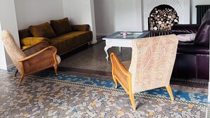 A living room with a sofa, two chairs, a fireplace, a television, and a patterned floor.