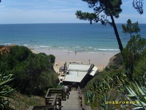 A beach view with a wooden staircase leading to a covered area overlooking the ocean. - Casa da Praia 
3 minutes walk from Olhos de Agua beach (Olhos de Agua)