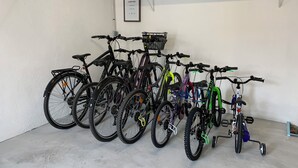 Várias bicicletas estacionadas encostadas a uma parede em uma garagem.
