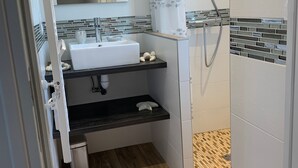 Uma casa de banho moderna com uma pia branca, um espelho, um chuveiro com cortina e um chão em mosaico.