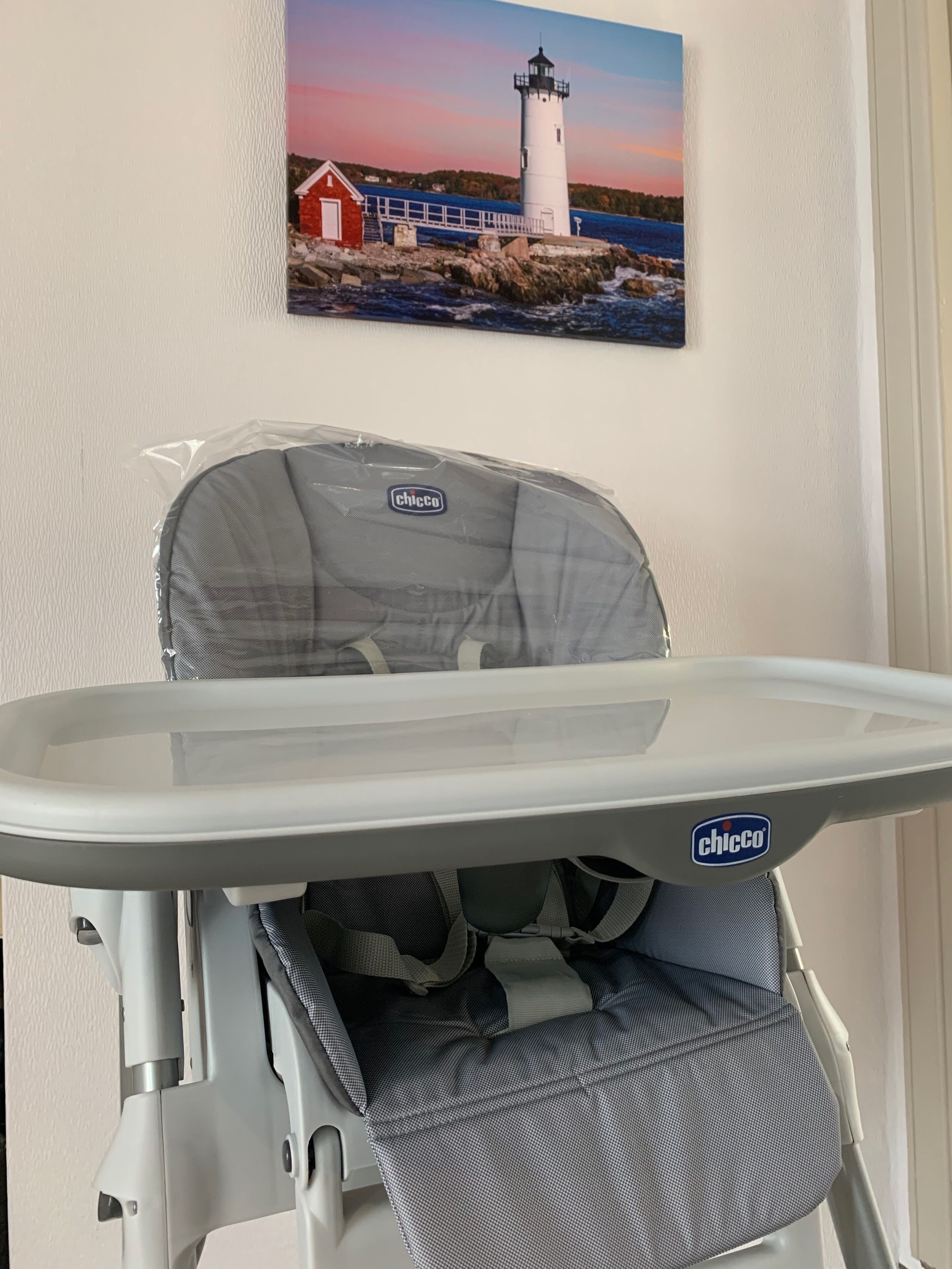 Een kinderstoel met een dienblad, een Chicco logo en een veiligheidsgordel.