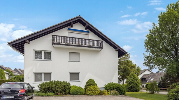 A two-story house with a balcony, a driveway, and a car parked in front. - Gorgeous apartment in Hildfeld with WiFi (Hildfeld)