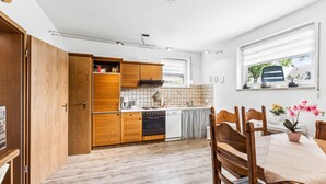 A compact kitchen with wooden cabinets, a dining area with a table and chairs, and a window with a view of the outside. - Gorgeous apartment in Hildfeld with WiFi (Hildfeld)