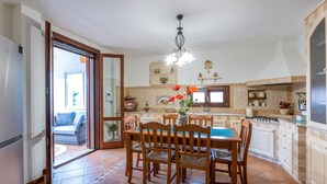 Un área de comedor con una mesa y sillas, un jarrón con flores y una cocina al fondo.