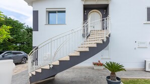 Un edificio moderno con una escalera curva, un ventanal pequeño y una puerta.