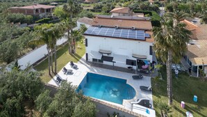 Una casa con piscina, paneles solares y jardín.