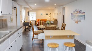 Una cocina moderna con armarios blancos, una isla central con taburetes y una zona de comedor con una mesa redonda y sillas.