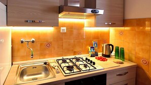 A kitchen with a gas stove, sink, and wooden cabinets.