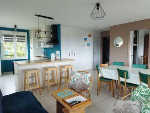 Eine moderne Küche mit Kochinsel, Barhocker und Essbereich mit Tisch und Stühlen.