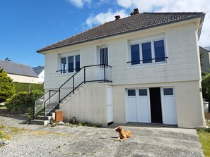 Een herenhuis met een veranda, een trap en een hond die op de grond zit.