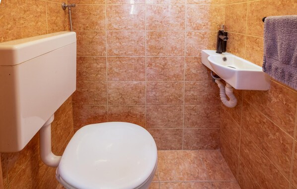A small bathroom with a toilet, a sink, and a towel hanging on the wall.