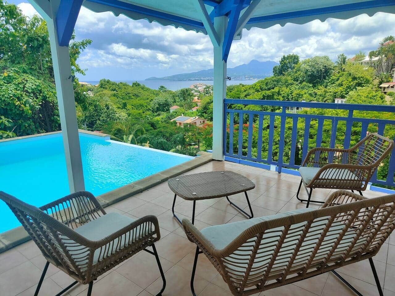 Área externa coberta com piscina, móveis de vime e vista para uma paisagem montanhosa.