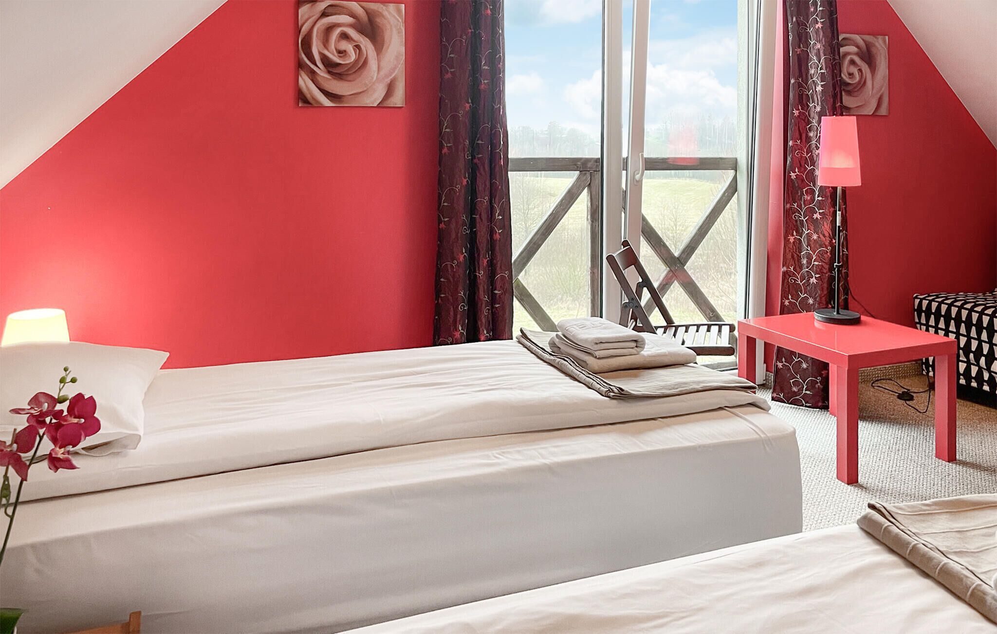 Un dormitorio con dos camas, una mesita, una silla y vistas al exterior.