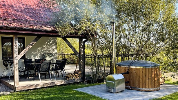 Eine Terrasse mit Gartenmöbeln, einem Grill und einem Whirlpool.