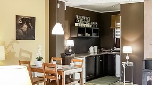 Eine kompakte Küche mit Essbereich, ausgestattet mit einem Holztisch, Stühlen und Pendelleuchten.