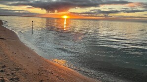 Una spiaggia con un tramonto sull'acqua, un'antenna e una riva sabbiosa.