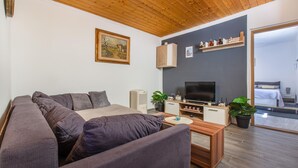 Un salon moderne comprenant un canapé, une table basse, un téléviseur et des objets de décoration.