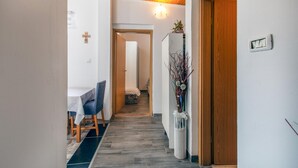 Un couloir avec un plafond en bois, un coin repas avec une table et des chaises, et un escalier menant à une autre pièce.