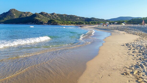 A beach with clear blue water, sandy shore, and a mountain in the background. - 2 bedroom cozy home in Is Molas (Is Molas)