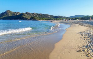 A beach with clear blue water, sandy shore, and a mountain in the background. - 2 bedroom cozy home in Is Molas (Is Molas)