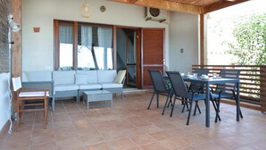 A covered patio with a sofa, chairs, and a table. - 2 bedroom cozy home in Is Molas (Is Molas)
