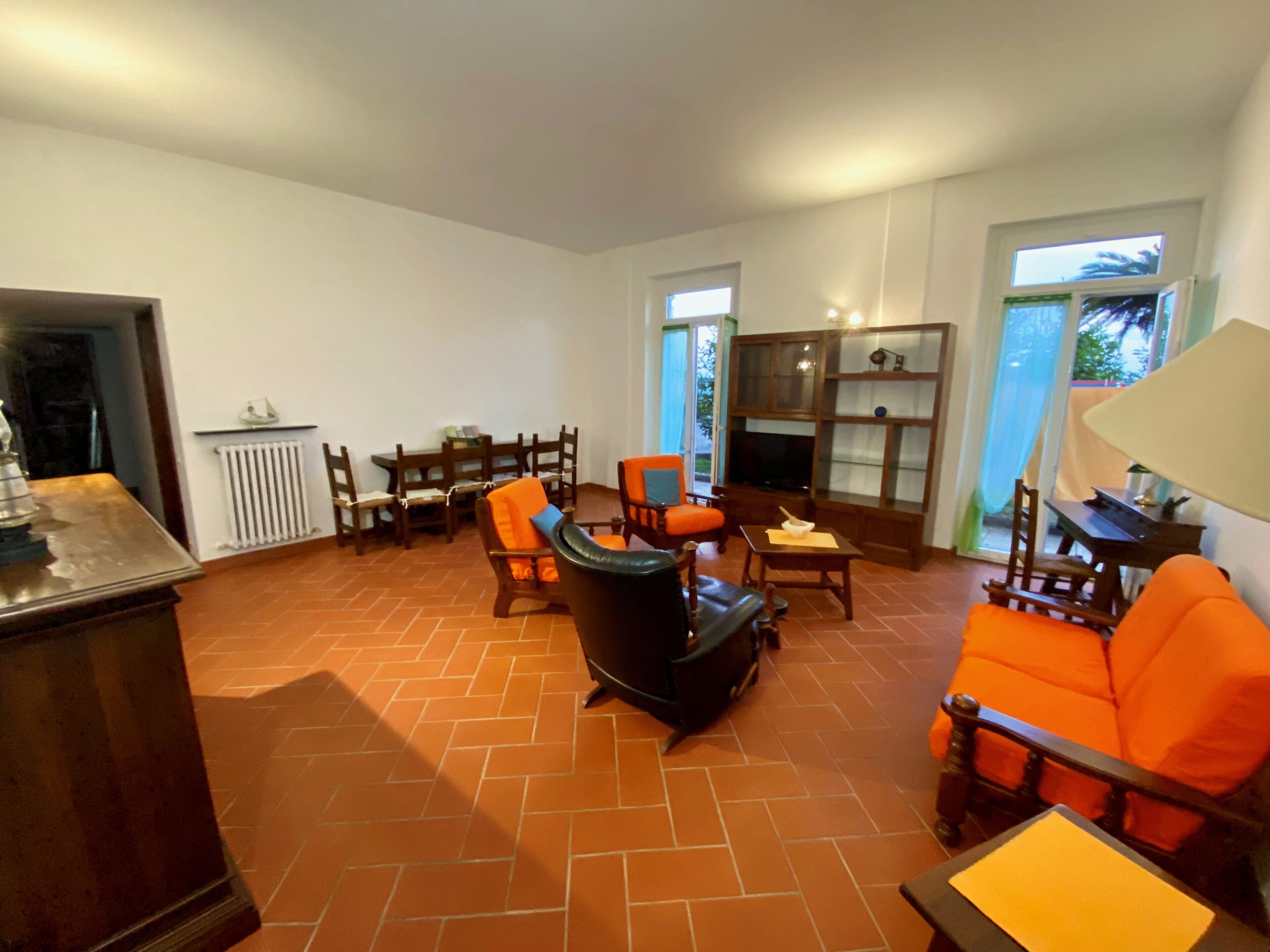 A spacious living room with a fireplace, a dining area, and a view of the outdoors through large windows.