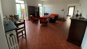 Un vaste espace de vie doté d’un sol carrelé, d’un téléviseur et de fauteuils orange et noirs.