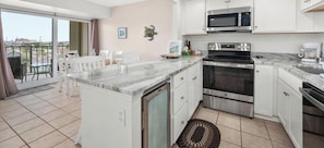 Una cocina con una isla central, microondas, horno y cafetera.