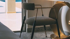 Een moderne kamer met uitzicht op de oceaan, een stoel, een tafel met een lamp en een grote spiegel.