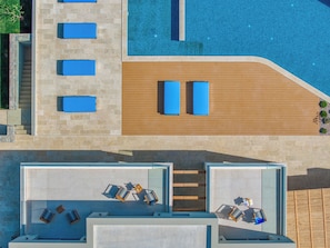 A rooftop pool area with blue lounge chairs, a wooden deck, and a view of the pool. - Villa Paradiso Mochlos with 5 Bedrooms, Infinity Pool, Jacuzzi,Olive Tree Garden (Sitia)