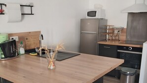 Eine moderne Küche mit einer zentralen Kochinsel, Barhocker, Kühlschrank, Mikrowelle und Spüle.