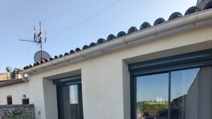 Eine moderne Terrasse mit Tisch und Stühlen, großen Schiebe-Glaskuppeln und einem Ziegeldach.