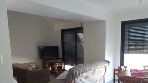 Ein Wohnzimmer mit einer Couch, einem Couchtisch, einem Fernseher und einem Essbereich mit Stühlen und Tisch.