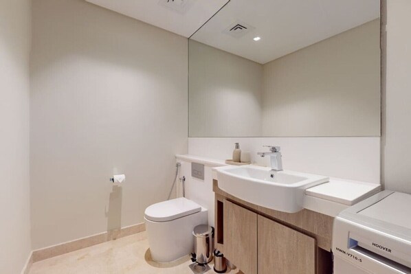 Un baño moderno con lavamanos, espejo y váter blancos.
