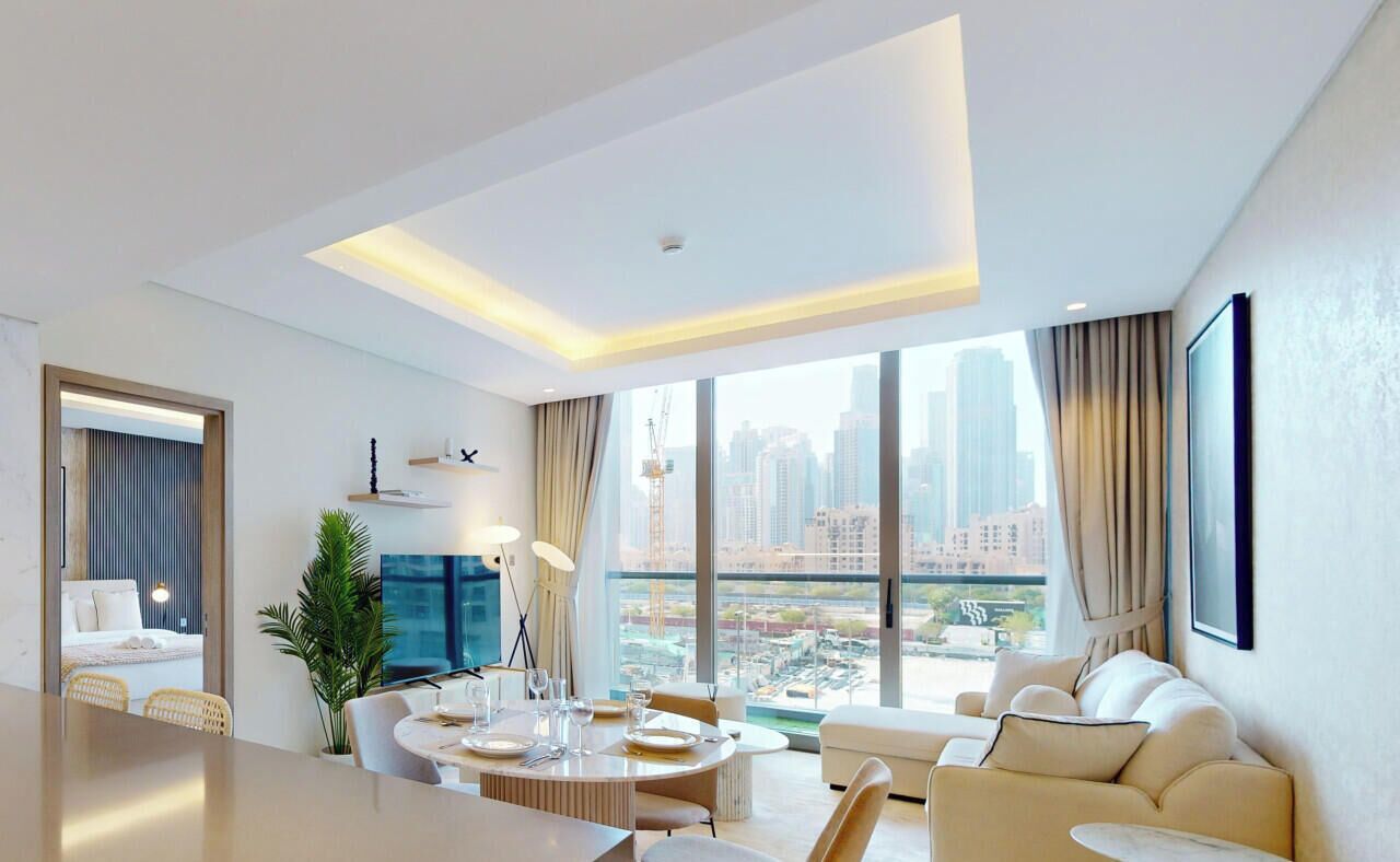 Ein modernes Hotelzimmer mit Essbereich, einer Couch und einem großen Fenster mit Blick auf die Stadt.