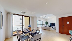 Relax in this spacious living area with a sofa, flat-screen TV, and sliding glass door leading to a balcony with a view.