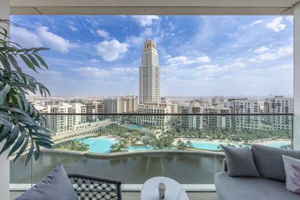 A balcony with a view of a tall building, a pool area, and surrounding residential buildings.