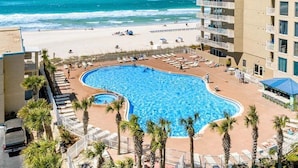 Ein Hotel mit großem Pool, umgeben von Palmen und Blick auf den Strand.