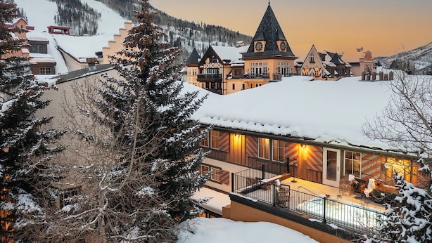 Una cittadina innevata con architettura tradizionale, tra cui un edificio importante con tetto a punta e un balcone con posti a sedere all'aperto.