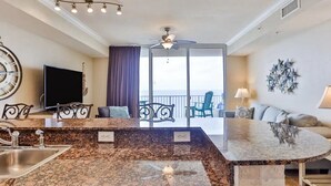 A modern kitchen with granite countertops, a built-in sink, and a ceiling fan.