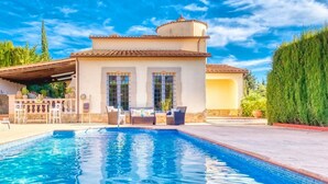 Una zona junto a la piscina con piscina, mobiliario de exterior y un edificio con tejado de azulejos.